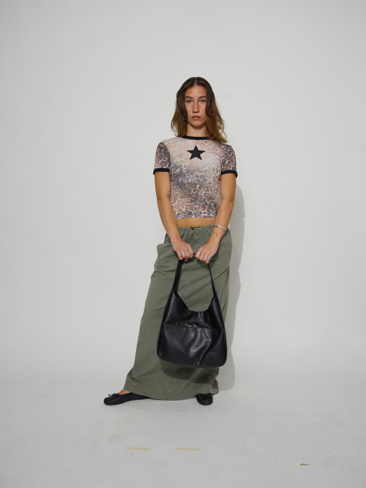 Kvinde i leopardmønstret bluse med stjerne, grønne bukser og sort taske. Mode, trendy tøj, stilfuldt outfit, moderne kvindemode.