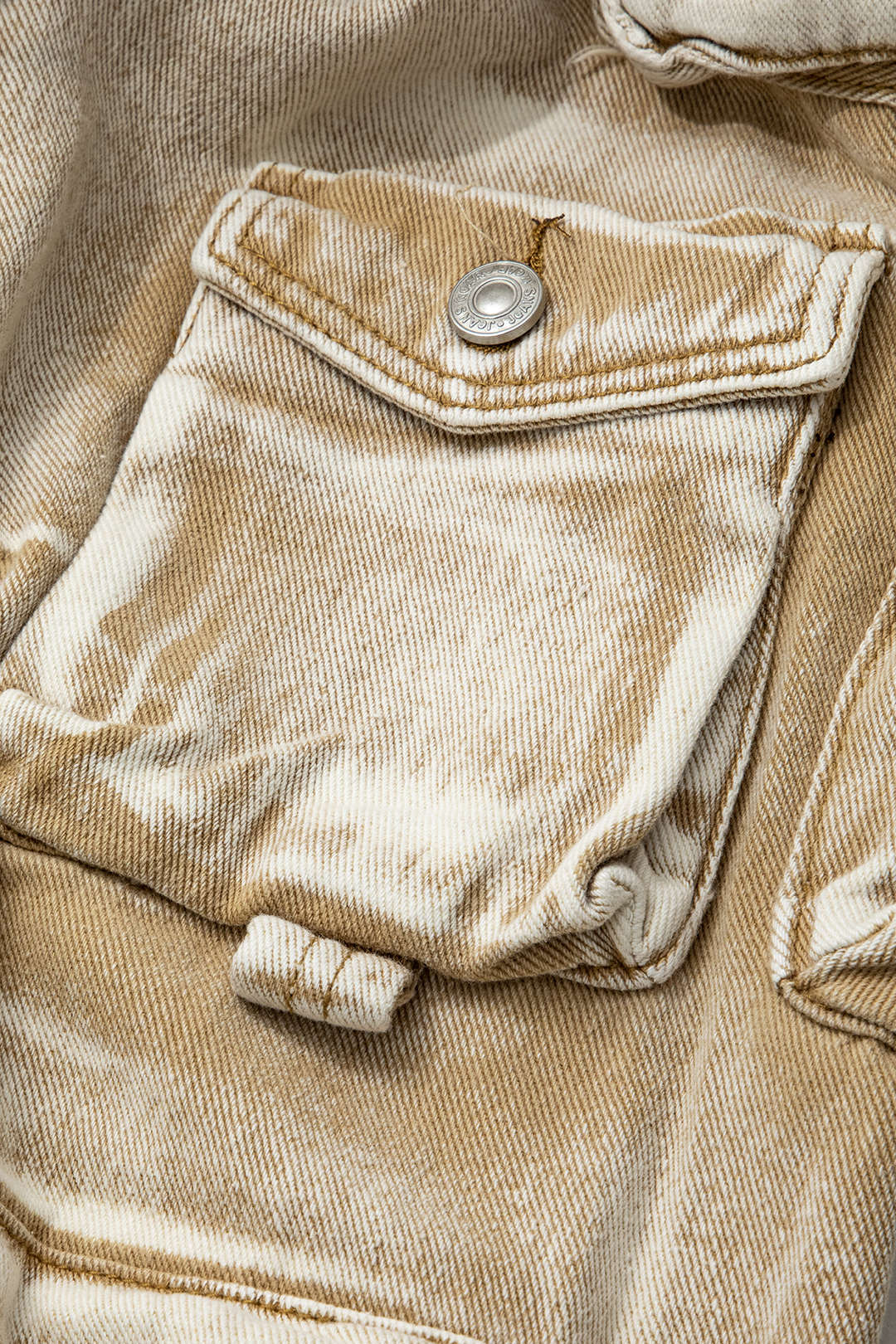 Beige denimjakke med brystlomme og knapdetalje, tie-dye mønster. Trendy mode, casual stil, unisex design, moderne tøj.