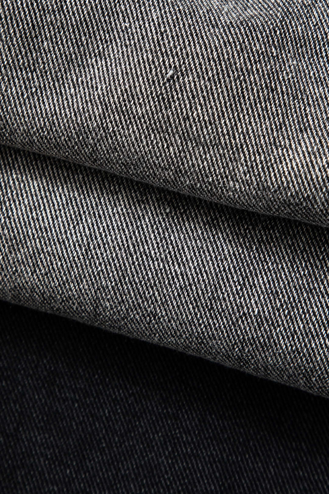 Grå og sort denimstof i nærbillede, viser tekstur og vævning. Perfekt til mode, tøjdesign og tekstilproduktion.