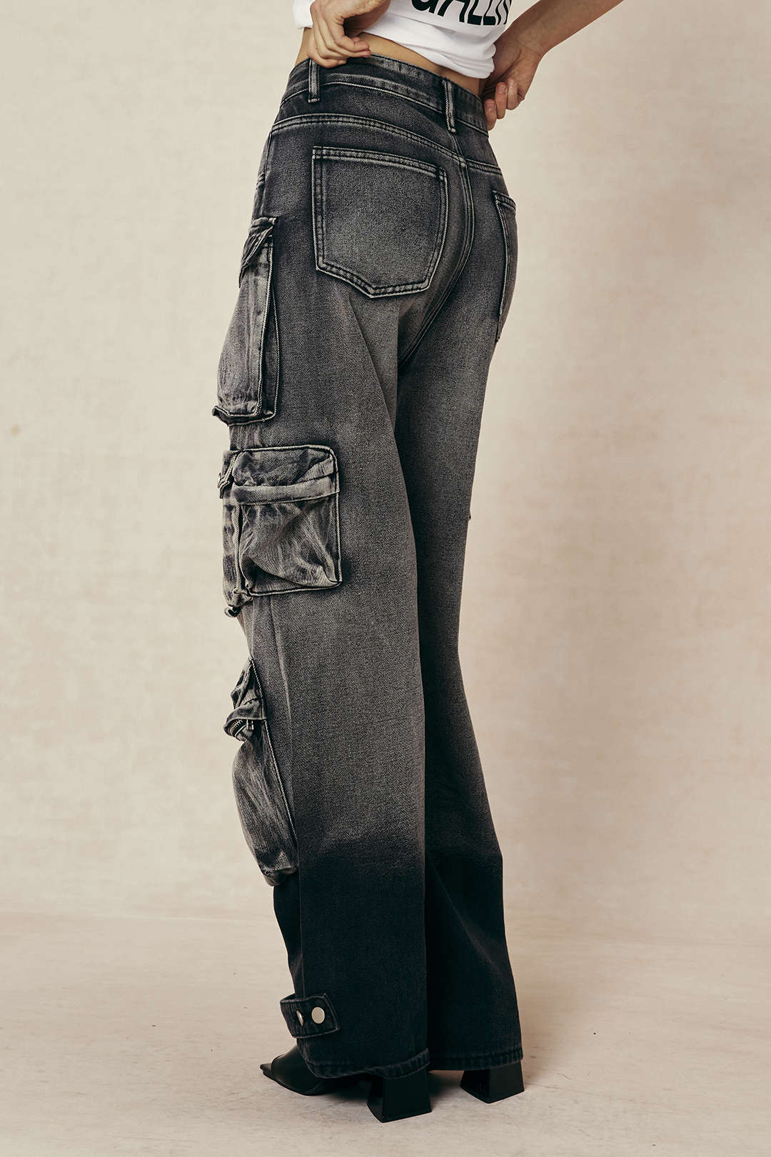Bagfra af kvinde iført sorte cargo-jeans med lommer, høj talje og vidde ben. Trendy streetwear-stil, perfekt til moderne mode.