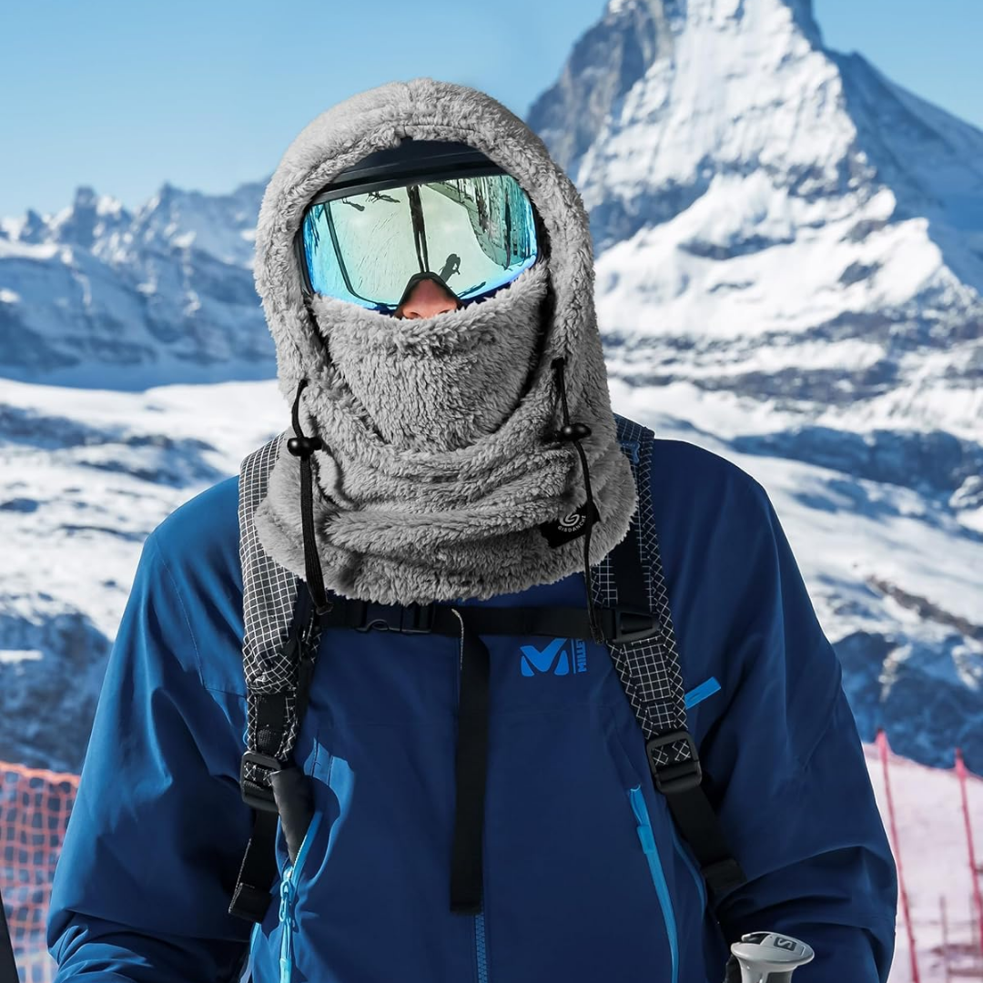 En person iført vintertøj og skibriller står foran Matterhorn-bjerget. Sneklædte bjerge i baggrunden. Vinter, ski, bjerglandskab, Schweiz.