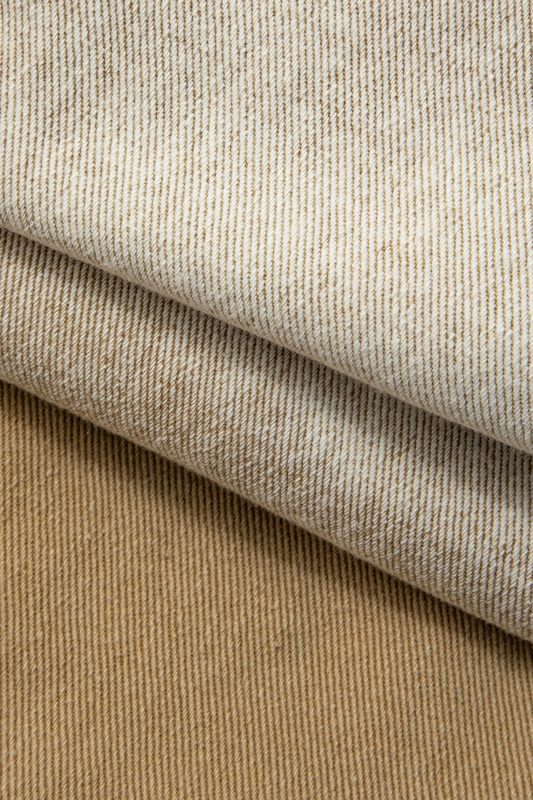 Beige og hvidt stribet stof, tæt tekstur, foldet lag, tekstilmateriale, velegnet til tøjdesign og boligindretning, moderne stofmønster.