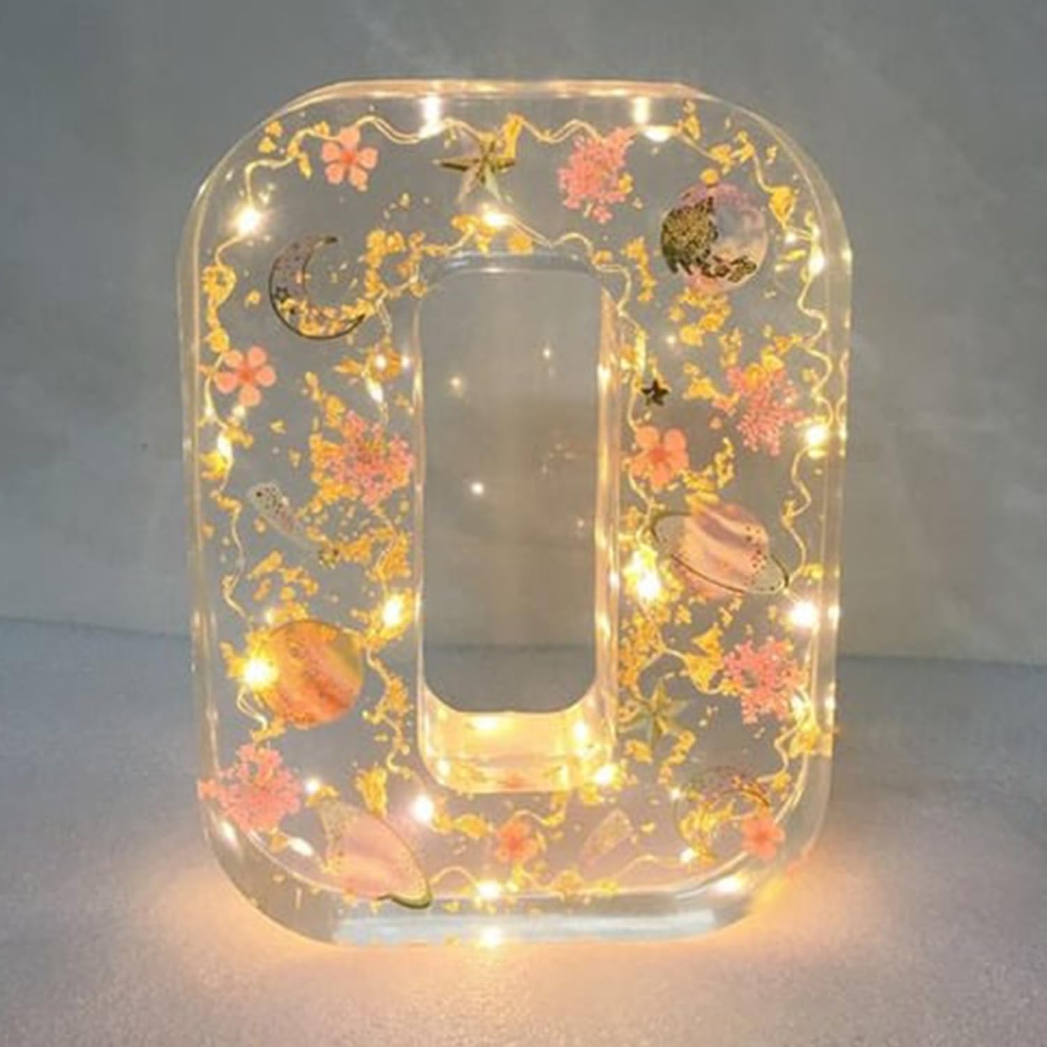 Dekorativt bogstav "O" med LED-lys, blomster og planetmotiver. Perfekt til hjemmedekoration, unik gaveidé, moderne interiørdesign.