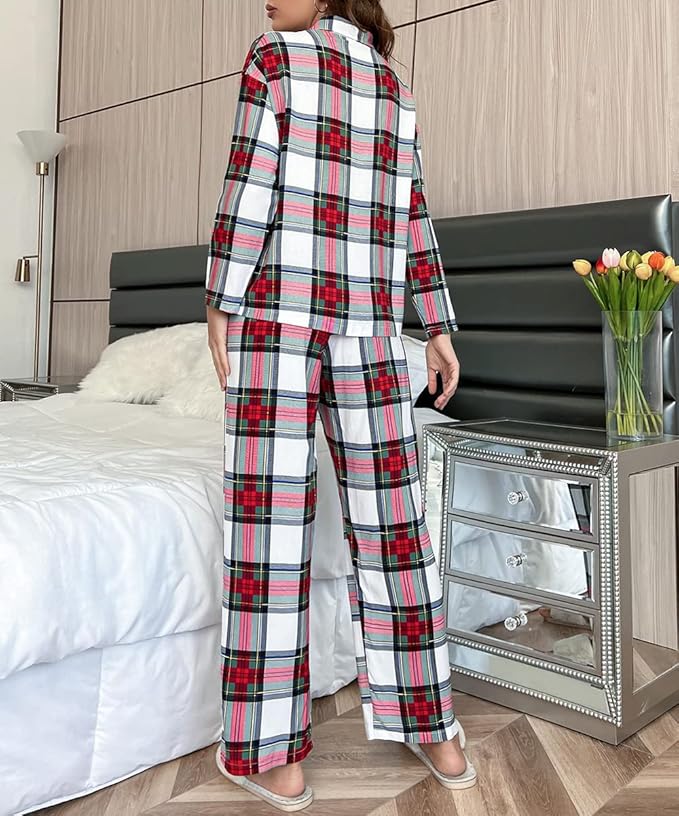 Kvinde iført rød, hvid og sort ternet pyjamas står ved siden af en seng i et moderne soveværelse med tulipaner på natbordet.