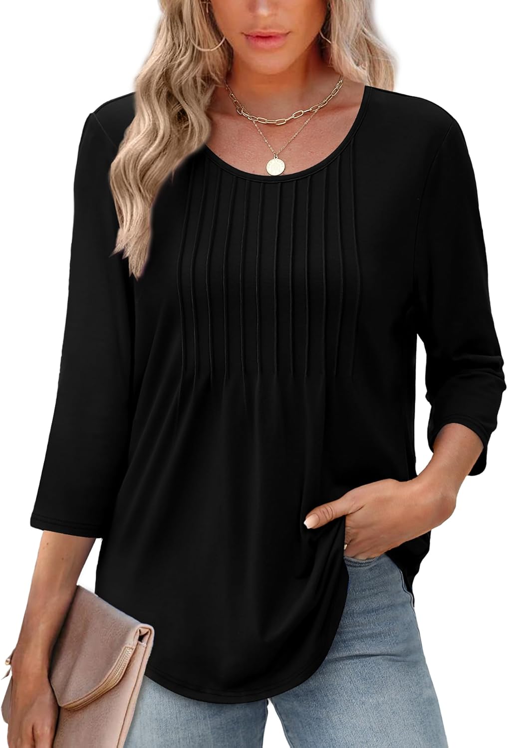 Kvinde iført sort bluse med trekvartærmer og plisseret front, kombineret med lyse jeans. Hun holder en beige clutch. Trendy og elegant look.