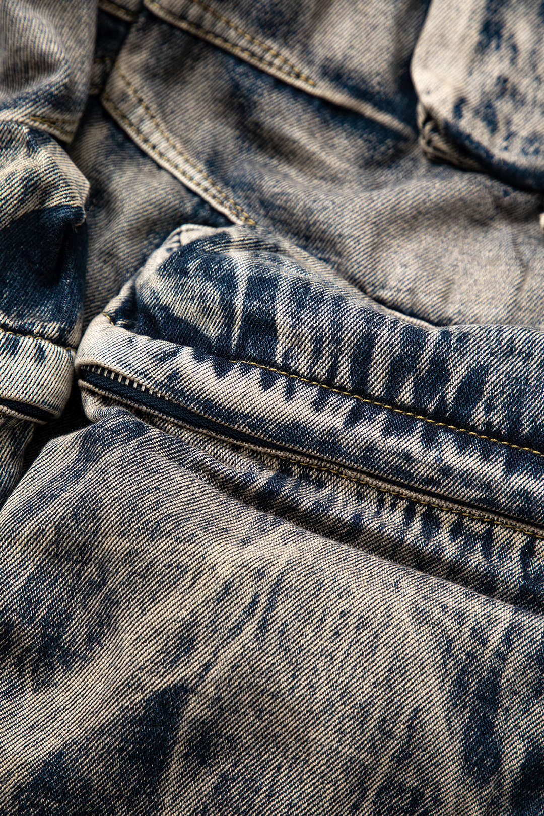 Slidt denimstof med lynlåsdetalje, viser klassisk blå jeans tekstur. Perfekt til mode, vintage tøj og denim trends.