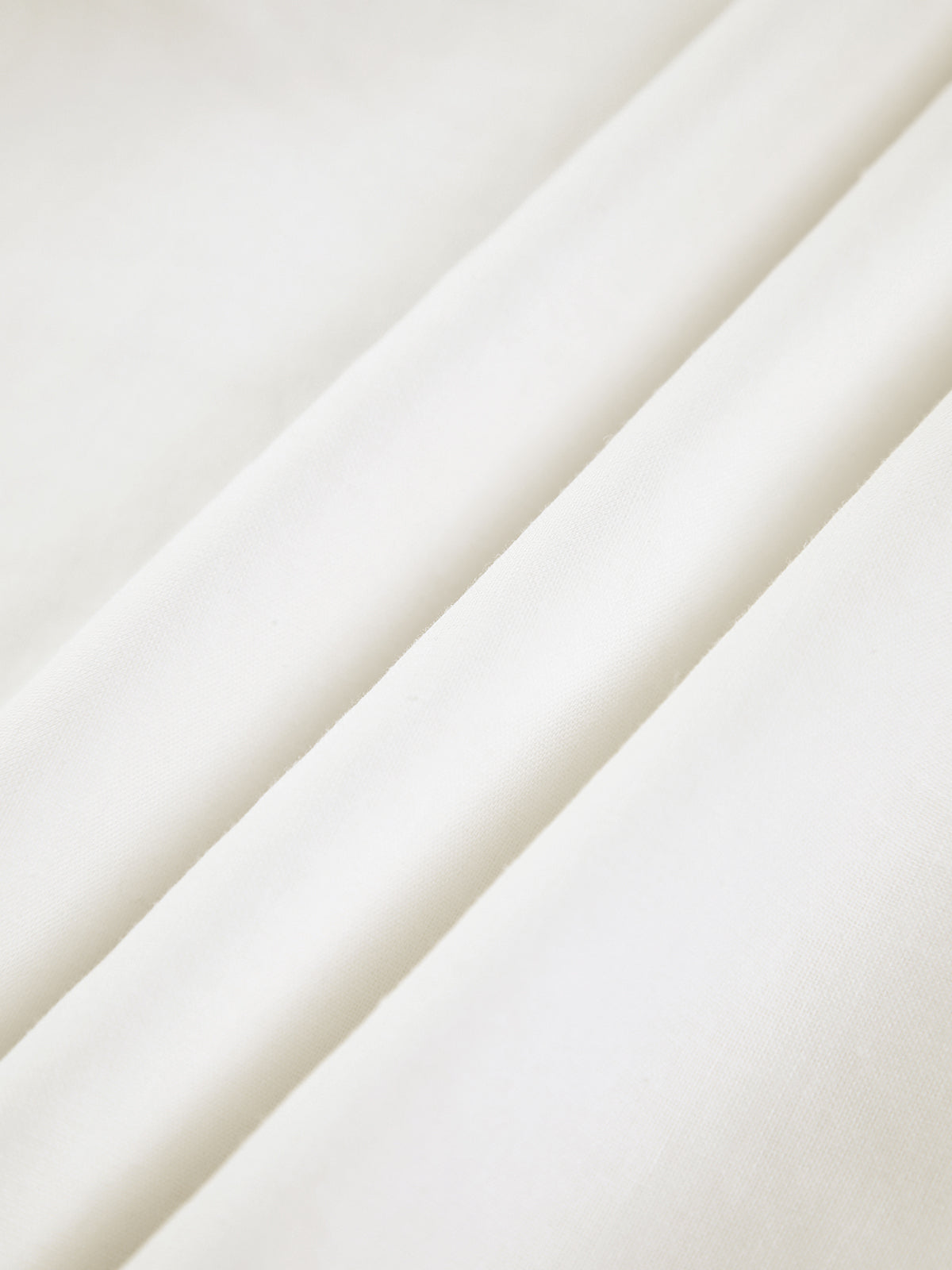 Hvidt bomuldsstof med bløde folder, tekstilmateriale, nærbillede. Perfekt til syning, mode og interiørdesign. Høj kvalitet, naturligt materiale.