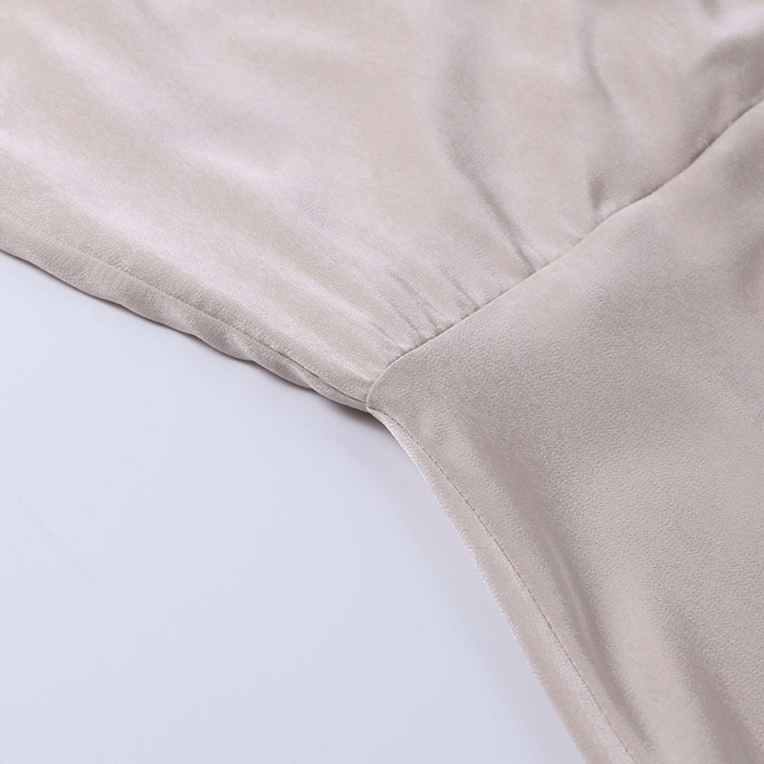 Beige silkestof med glat tekstur, tæt på syning. Luksuriøst materiale til tøjdesign, kjoler eller sengetøj. Høj kvalitet, elegant og blødt.