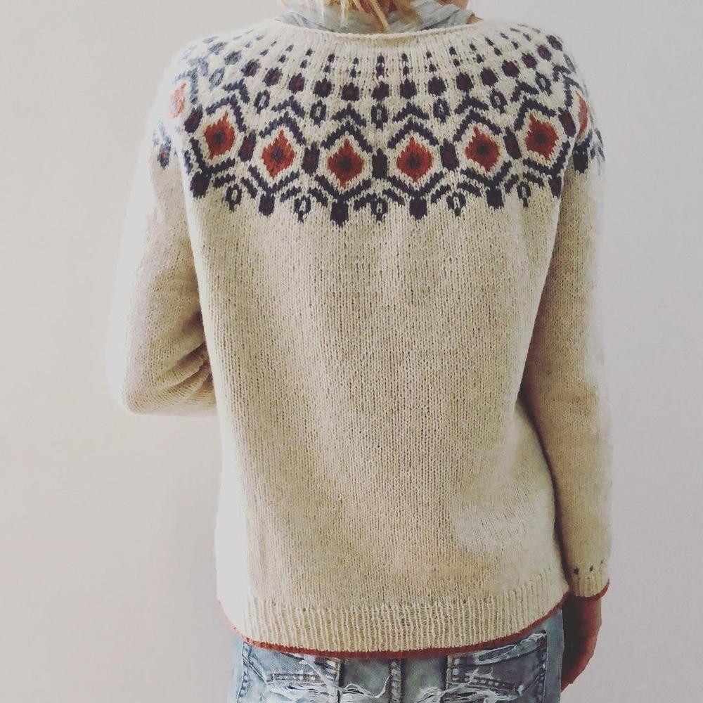 Beige striktrøje med nordisk mønster i sort og rød, set bagfra. Perfekt til vintermode og hygge. Striktrøje, nordisk design, vintertøj.