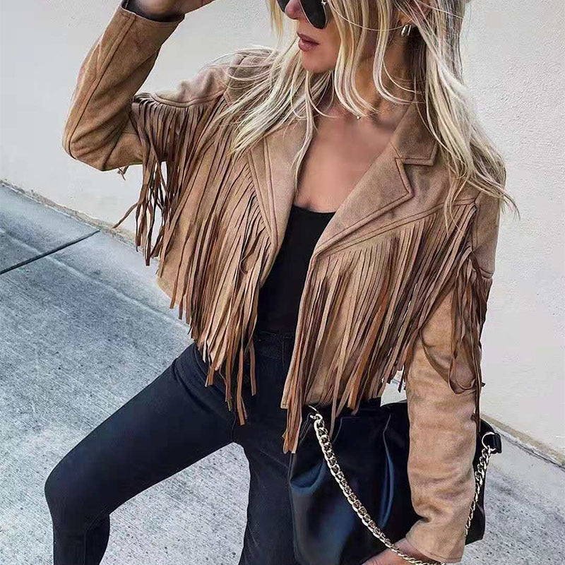 Blond kvinde i brun ruskindsjakke med frynser, sorte solbriller og sort taske med kæde. Mode, street style, trendy outfit, moderne kvindetøj.