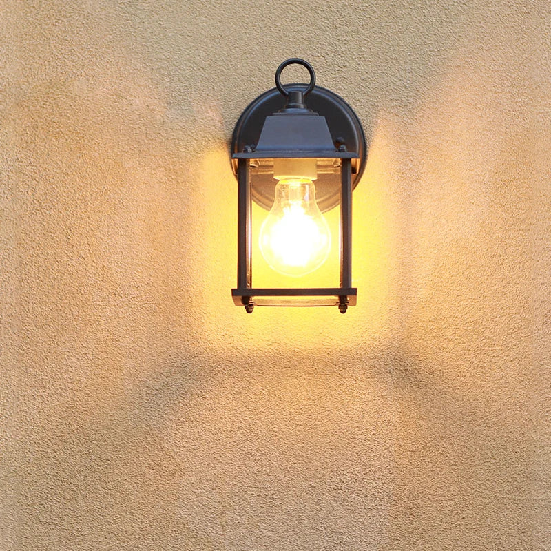 Udendørs væglampe i vintage stil med glødepære, monteret på en beige væg. Ideel til belysning af have eller terrasse. Energibesparende belysning.