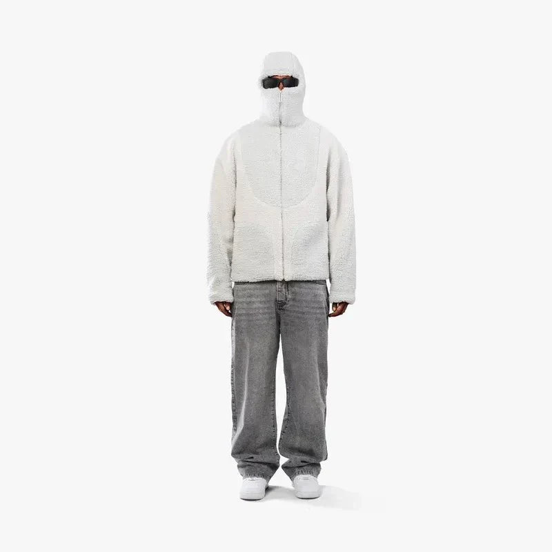 Person iført grå hættetrøje med lynlås, solbriller og grå jeans. Moderne streetwear stil, minimalistisk design, urban mode.