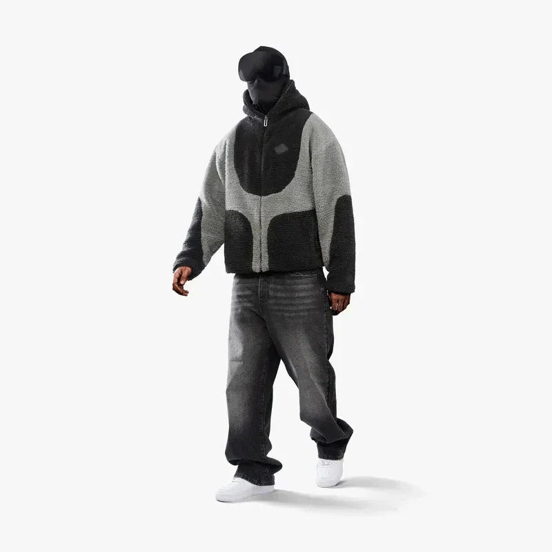 Sortklædt person i moderne, grå og sort fleecejakke, baggy jeans og hvide sneakers. Futuristisk mode, streetwear, minimalistisk stil.