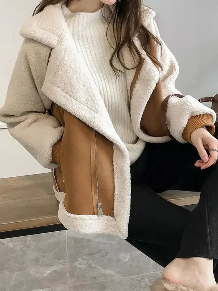 Kvinde iført trendy, varm teddyjakke i beige og brun med lynlås, sidder afslappet. Perfekt til vintermode og stilfuldt vintertøj.