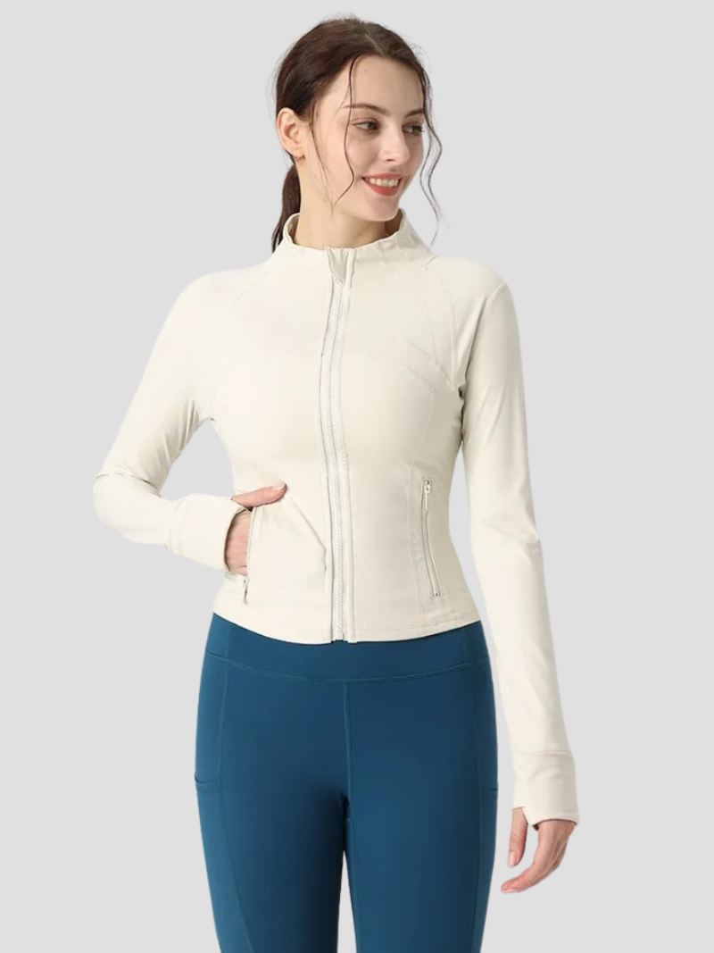 Kvinde iført hvid træningsjakke med lynlås og blå leggings. Sportstøj, aktivt liv, komfortabelt design. Fitnessmode, moderne kvindetøj.