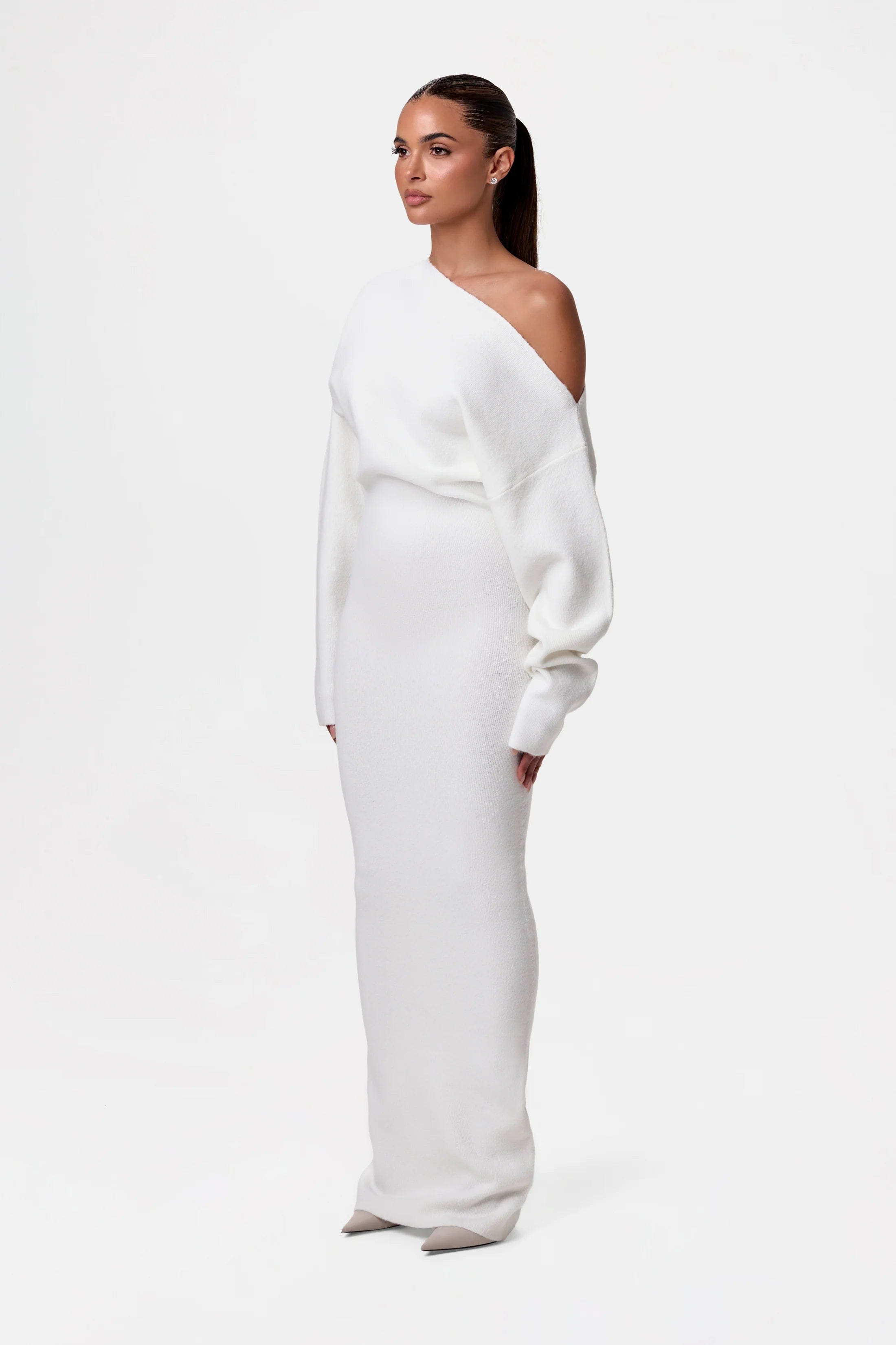 Kvinde i elegant, hvid, langærmet kjole med asymmetrisk skulderdesign. Perfekt til mode, minimalistisk stil og moderne kvindetøj.