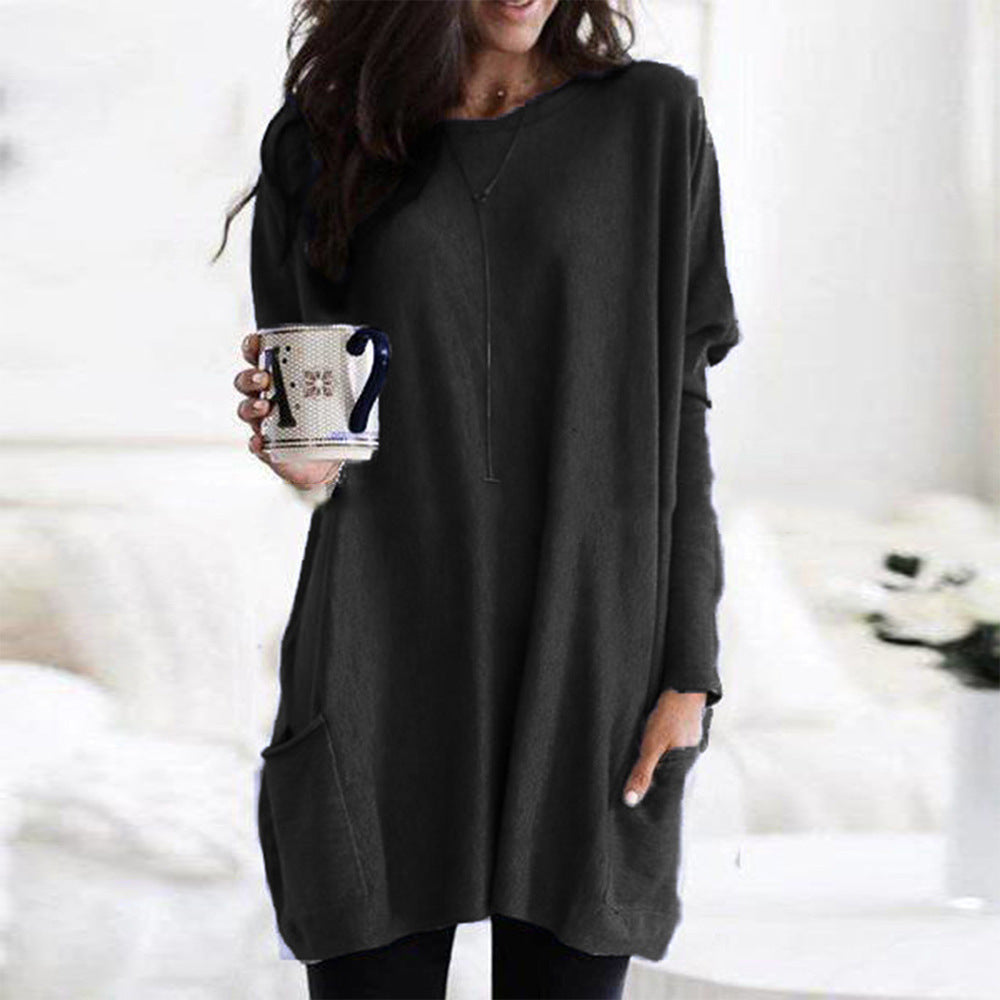 Kvinde iført sort, langærmet tunika med lommer, holder en mønstret kaffekop. Stilfuldt og afslappet look, perfekt til hverdagsbrug.