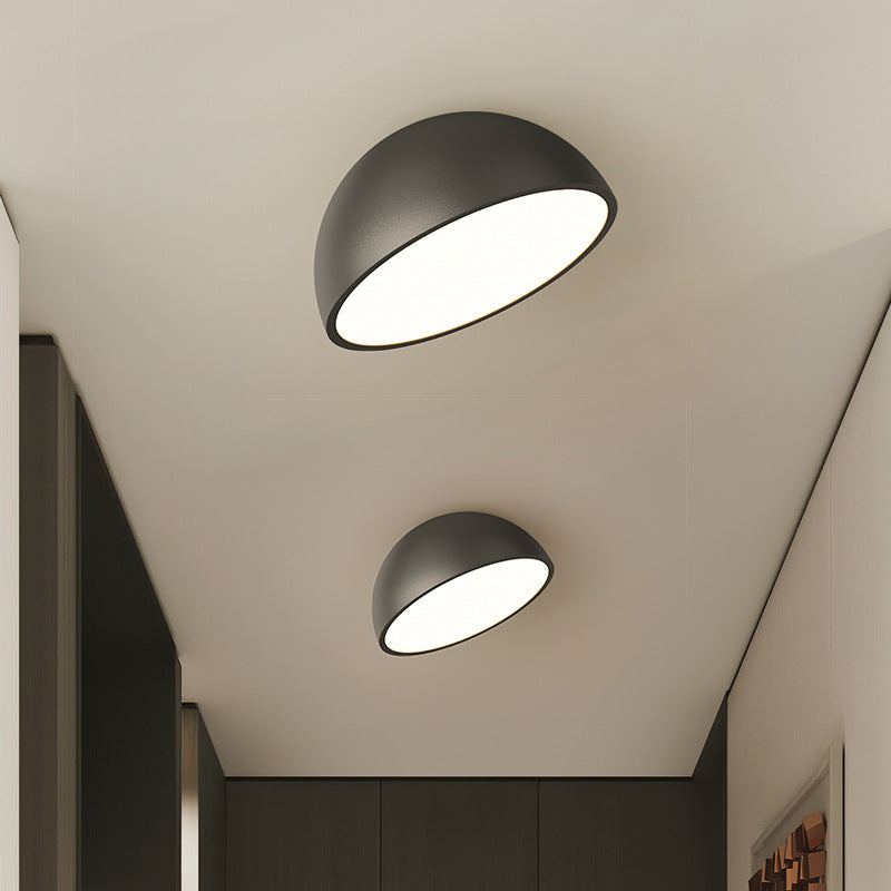Moderne sort loftslampe i halvcirkelformet design, monteret i hvidt loft. Energibesparende LED-belysning til stilfuld indretning.
