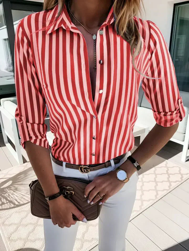 Kvinde i rød-hvid stribet skjorte, hvidt bælte og hvide bukser, holder brun taske. Mode, stilfuldt outfit, moderne kvindetøj, udendørs.