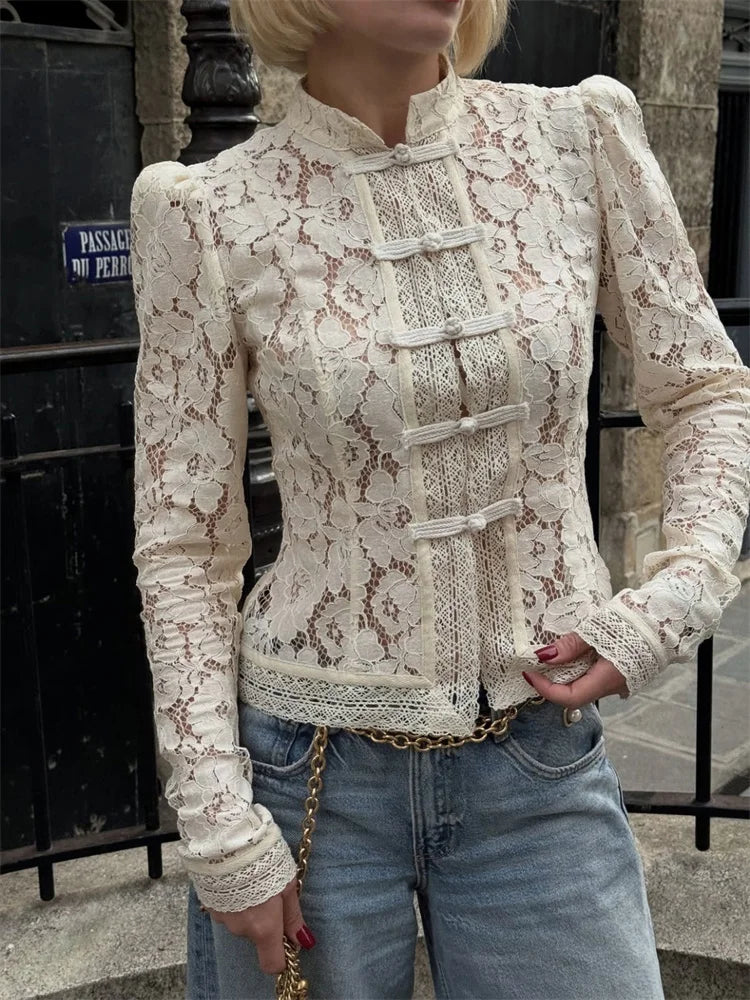 Kvinde iført hvid blondebluse med knapper, kombineret med blå jeans. Elegant og stilfuldt outfit til gadebillede. Mode, tøj, street style.