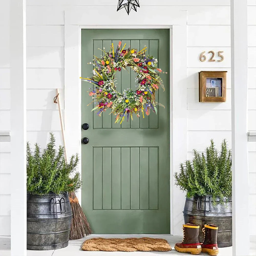 Grøn dør med farverig blomsterkrans, flankeret af to store urtepotter med rosmarin. Indgangsparti med kost og nummer 625. Hyggelig forårsdekoration.