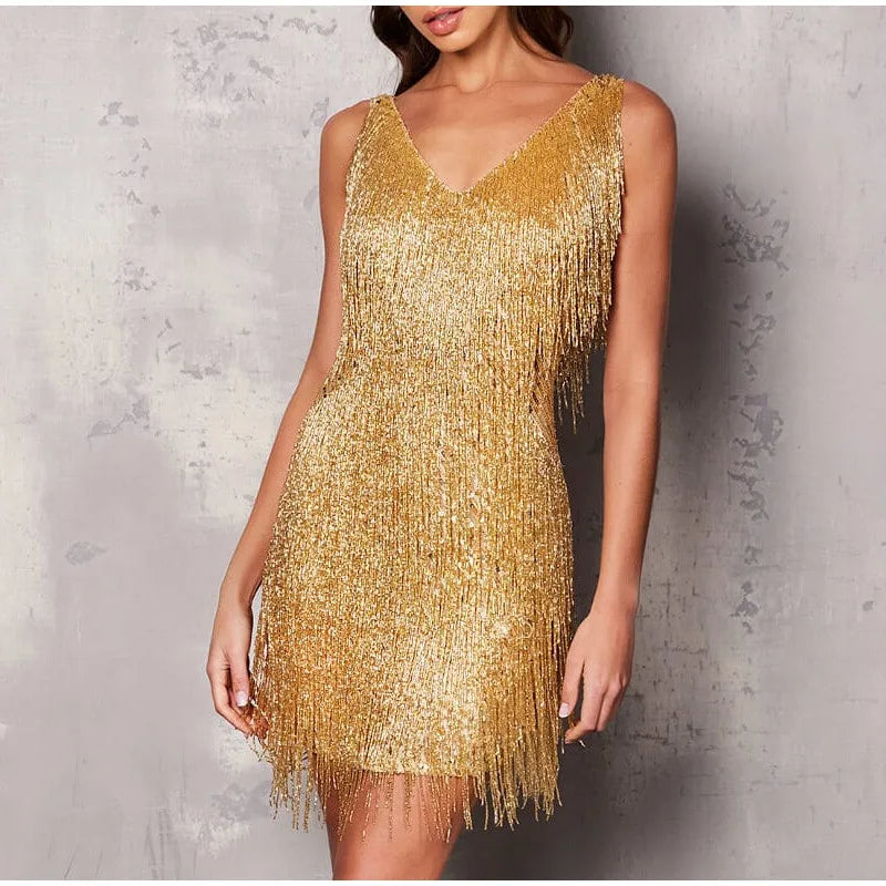 Kvinde i en glitrende guld pailletkjole med frynser, perfekt til fest eller aftenbegivenheder. Elegant og stilfuldt design.