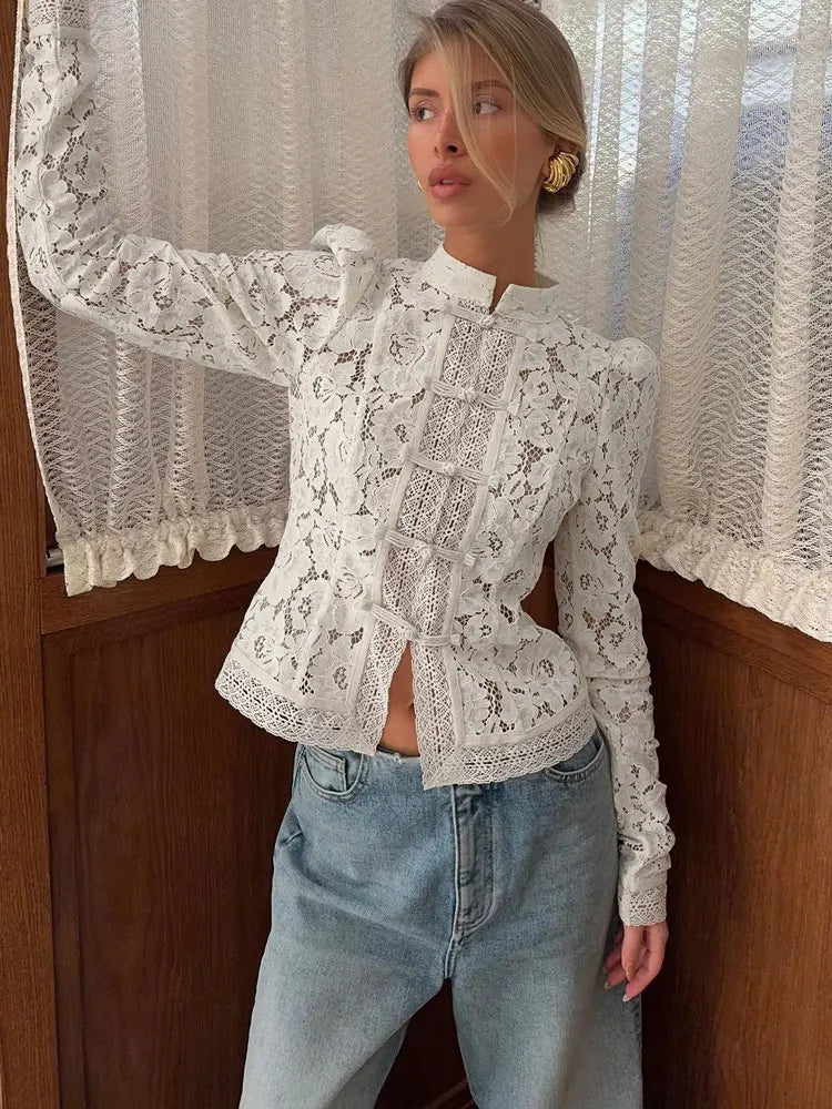 Ung kvinde iført hvid blondebluse og lyseblå jeans foran gardin. Mode, stilfuldt tøj, moderne kvindemode, casual outfit.