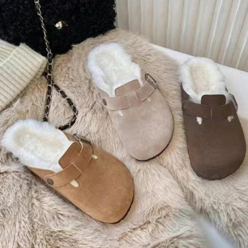 Tre par hjemmesko i ruskind med hvidt plysfor, i beige, brun og lysebrun, ligger på en hvid overflade ved siden af en strikket sweater og en taske.