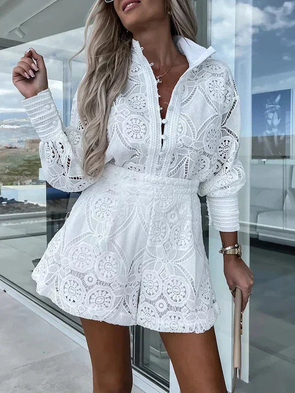 Kvindelig model i hvid, blonderet jumpsuit med lange ærmer, stående på altan. Sommermode, elegant design, moderne kvindetøj.