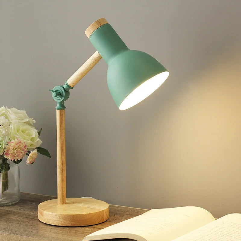 Grøn bordlampe i træ på skrivebord ved siden af åben bog og blomster. Moderne design, belysning til kontor eller studie. Skandinavisk stil.