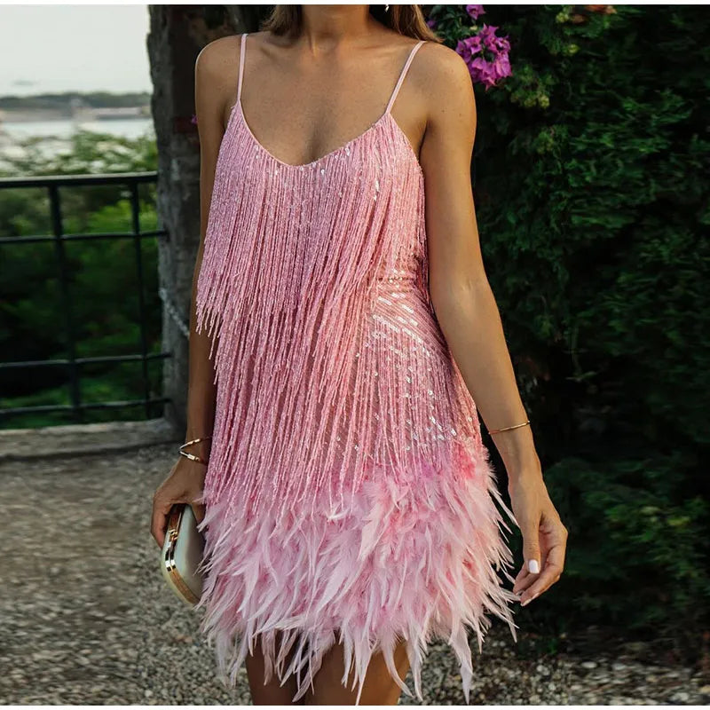 Kvinde i lyserød pailletkjole med frynser og fjer, elegant festkjole, udendørs baggrund, sommermode, trendy aftenlook.