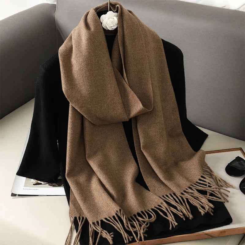 Brun kashmir tørklæde med frynser på grå sofa. Luksuriøst vintertilbehør, blødt og stilfuldt. Perfekt til modebevidste i koldt vejr.