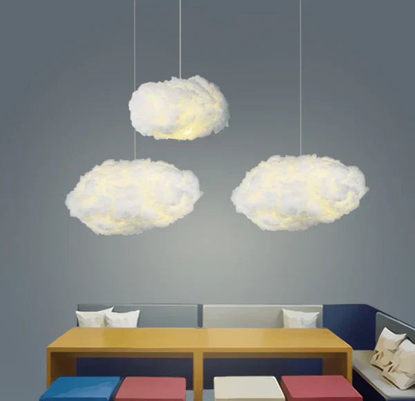 Tre skyformede loftslamper hænger over et moderne spisebord med farverige puder. Stilfuld belysning, moderne indretning, skandinavisk design.