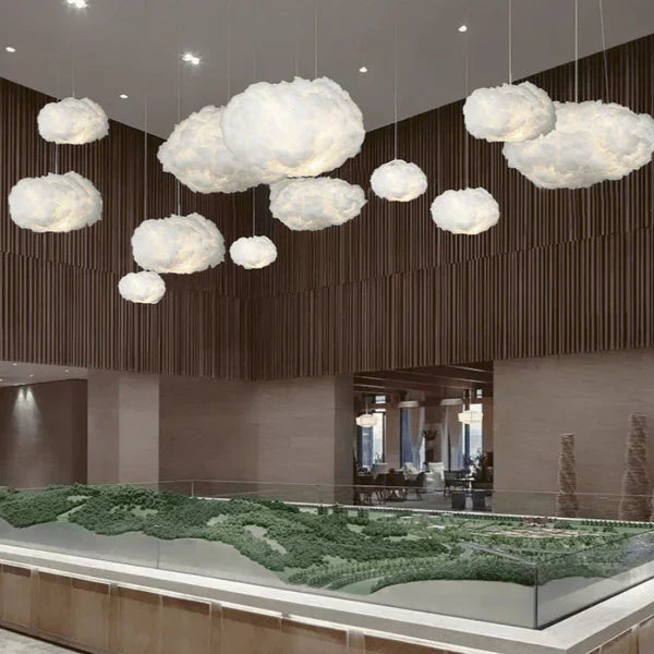 Skyformede lamper hænger i moderne indretning over en detaljeret arkitekturmodel. Unik belysning, kreativt design, interiørinspiration.