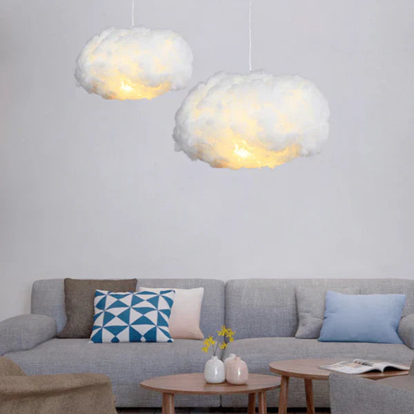 To lamper formet som skyer hænger over en grå sofa med farverige puder i en moderne stue. Perfekt belysning til skandinavisk indretning.
