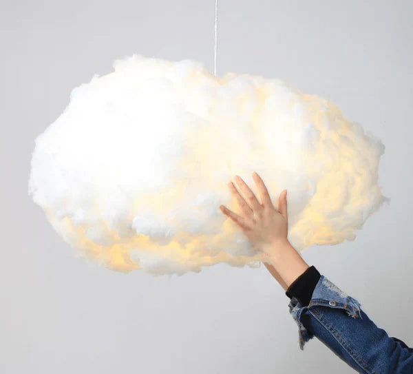 Hånd rører ved skyformet lampe, der hænger fra loftet. Kreativ belysning, moderne indretning, unik lampe, skyformet design.
