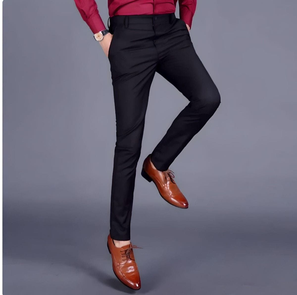 Mand i sorte bukser og brune lædersko, rød skjorte, grå baggrund. Elegant herremode, formelt tøj, stilfuldt look.