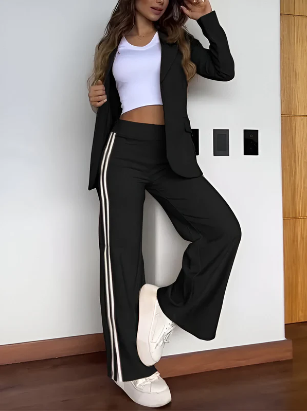 Kvinde iført sort jakkesæt med hvide striber, hvid top og sneakers. Moderne mode, afslappet stil, trendy tøj til kvinder.
