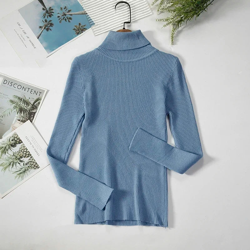 Blå rullekrave sweater i ribstrik på hvid baggrund med blade og magasiner. Stilfuld og moderne design til efterår og vintermode.