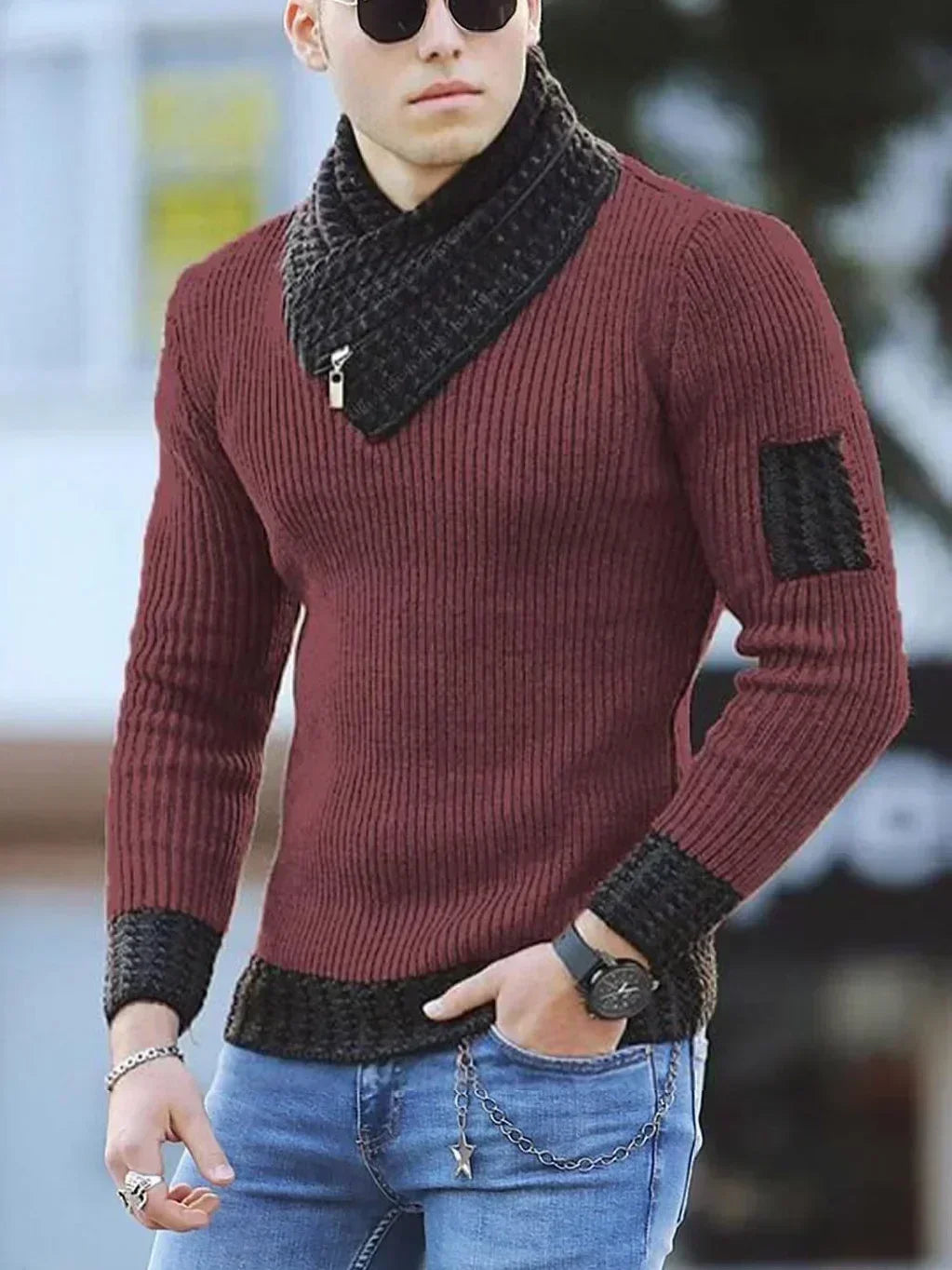Mand iført brun striktrøje med sorte detaljer, solbriller og jeans. Moderne herremode, vintertøj, stilfuldt design.
