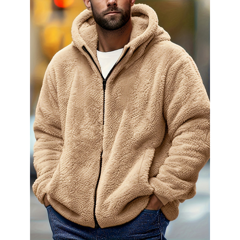 Mand iført beige teddyjakke med hætte, stående udendørs. Varm vintermode, trendy herrejakke, komfortabelt tøj til koldt vejr.