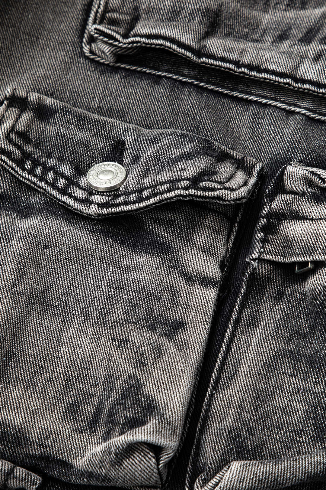 Grå denimjakke med lommer og knapdetaljer, tekstureret stof, mode, tøj, stilfuldt design, nærbillede, moderne beklædning.