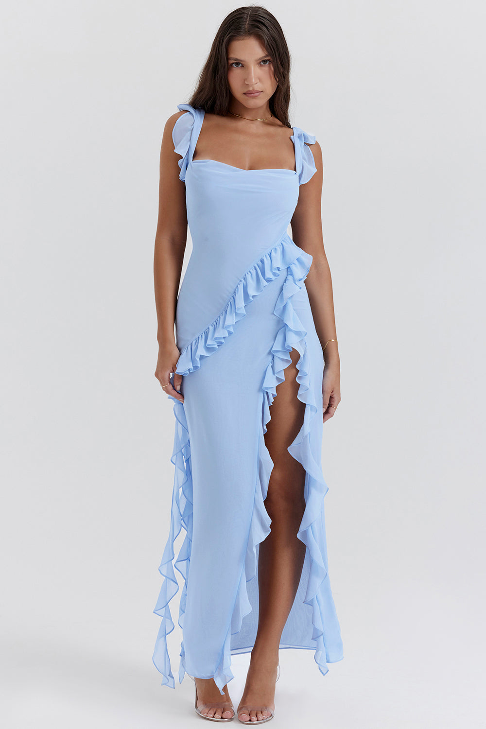 Kvinde i lyseblå kjole med flæser og høj slids, elegant design, sommermode, festkjole, stilfuldt look, moderne tøjstil, feminin elegance.
