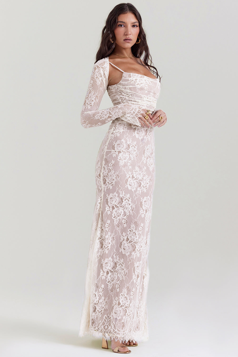 Kvinde i elegant, lang, hvid blondekjole med lange ærmer. Perfekt til bryllup eller formel begivenhed. Stilfuldt og tidløst design.