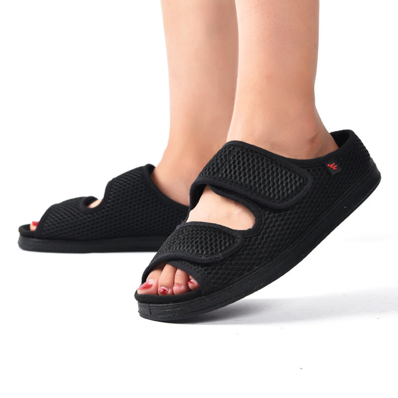 Sorte ortopædiske sandaler med velcro, åndbart mesh-design, bæres af person. Komfortable sko til daglig brug, ideelle til fodstøtte.