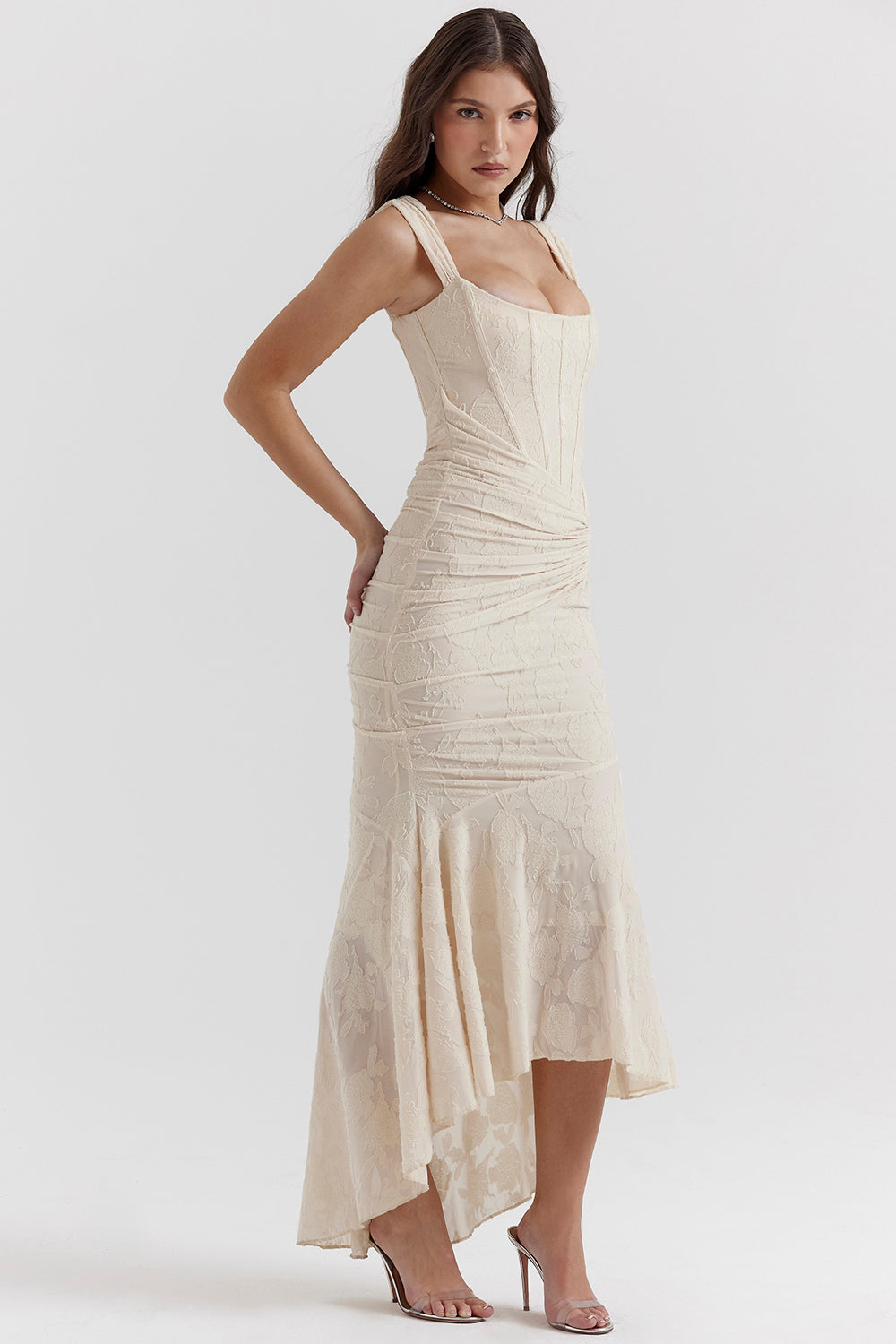 Kvinde i elegant, cremefarvet, ærmeløs kjole med asymmetrisk nederdel og blonder. Perfekt til festlige lejligheder. Mode, stil, aftenkjole.