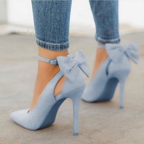 Lyseblå højhælede sko med sløjfer, bæres af person i stramme jeans. Elegant fodtøj, mode, stilfulde stiletter, kvindesko.