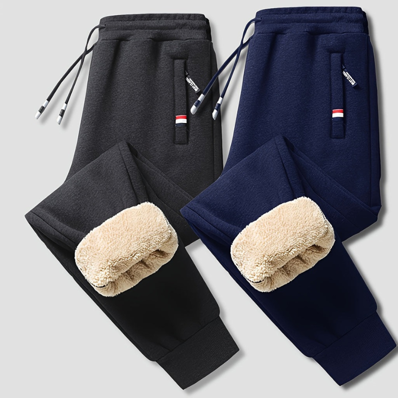 To par fleeceforede joggingbukser i sort og marineblå med snøre og lommer. Komfortable og varme bukser til mænd, ideelle til vinterbrug.