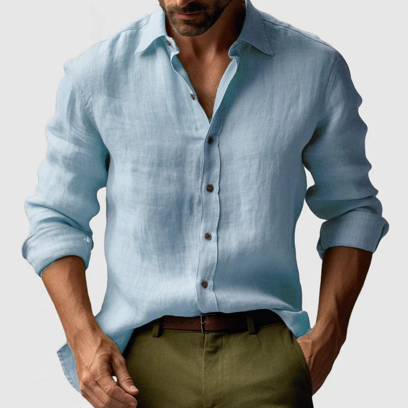 Mand iført lyseblå hørskjorte og olivengrønne bukser. Stilfuldt herretøj, afslappet look, moderne mode. Perfekt til sommer og forår.