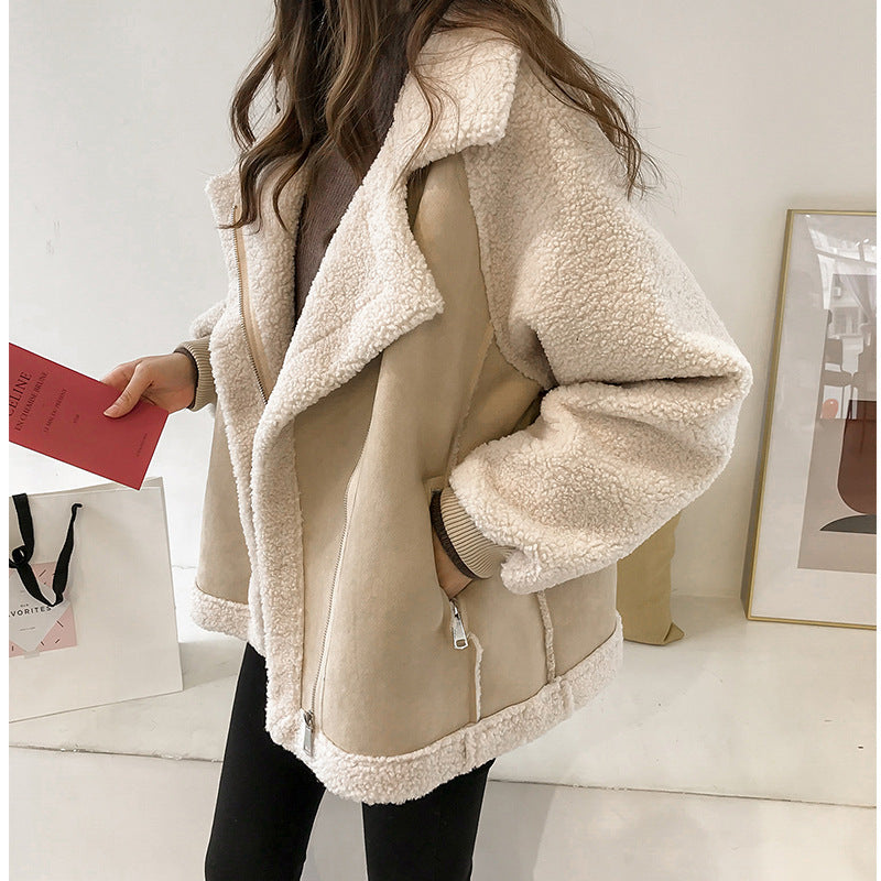 Kvinde iført trendy beige teddyjakke med hvidt plysfor, holder rød bog. Mode, vinterjakke, stilfuldt tøj, kvindemode, varm jakke.